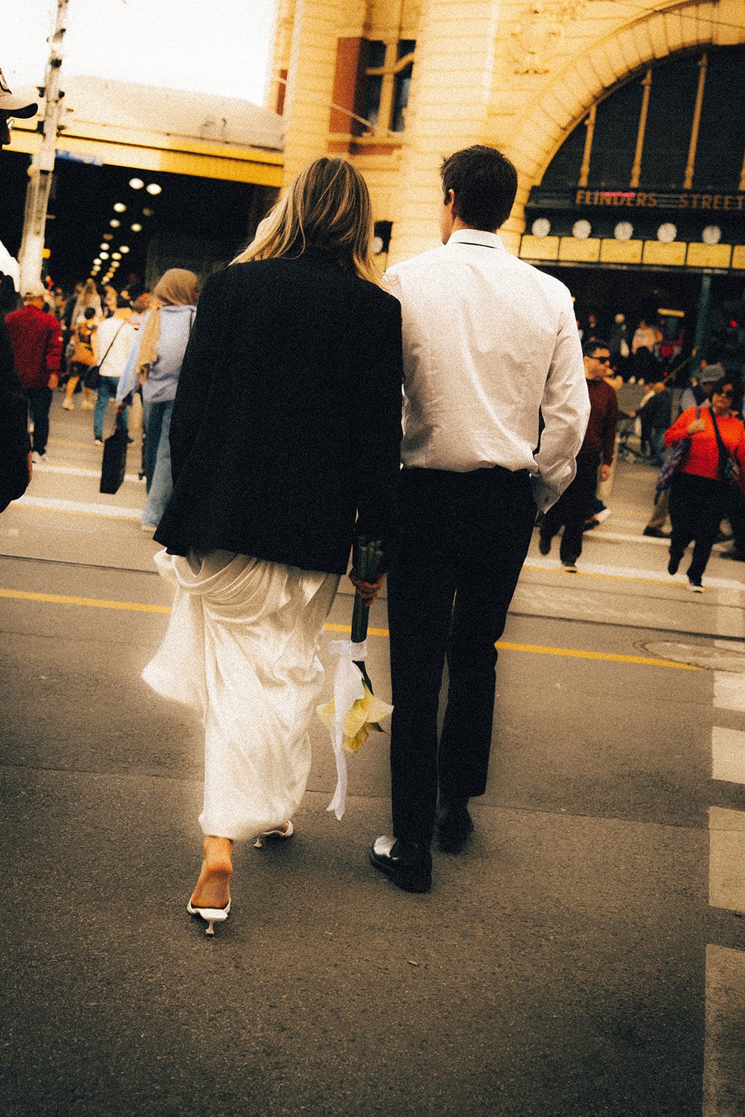 Hannah, wearing Josh’s jacket, walking with him through the crowd towards Flinders Street Station