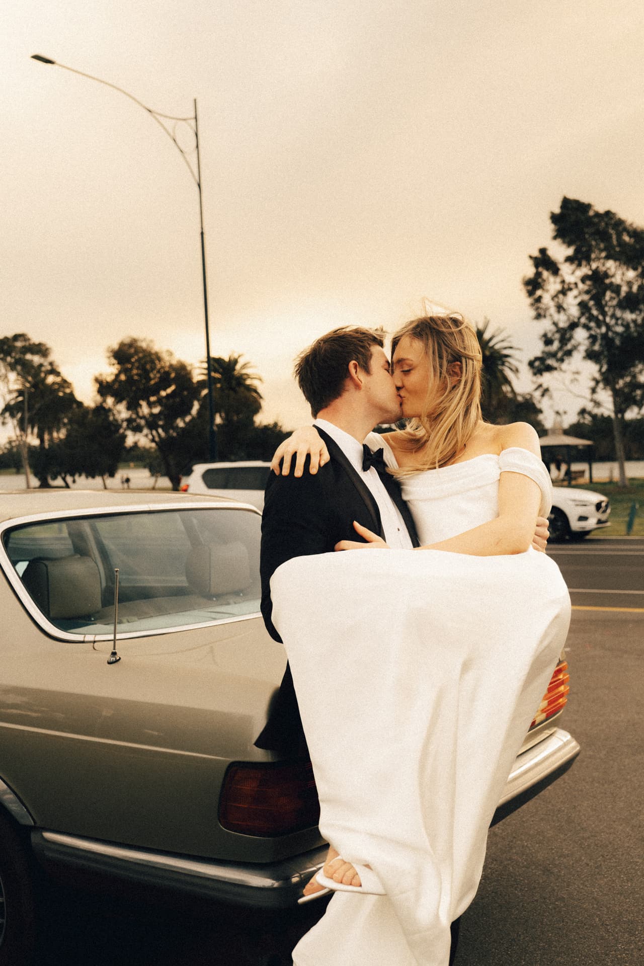 Josh kissing Hannah beside a vintage silver Mercedes
