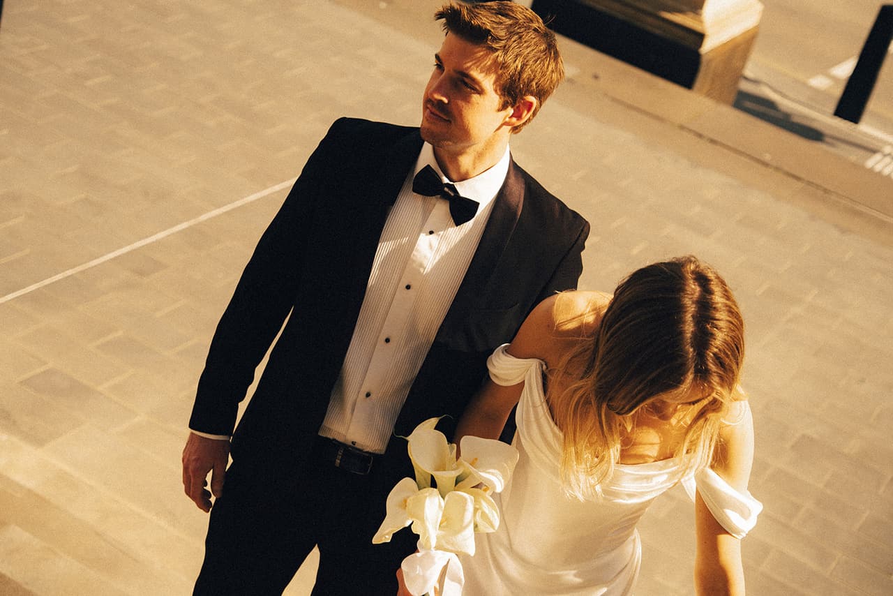 Josh and Hannah seen from above as they climb pale stone steps, calla lilies in her hand