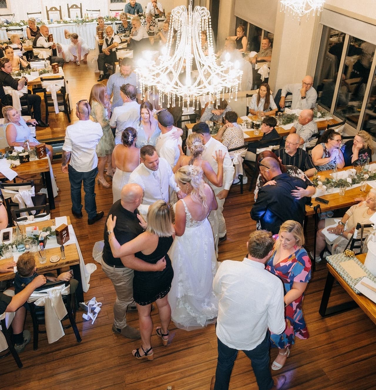 The packed dance floor seen from above, guests dancing between the long tables