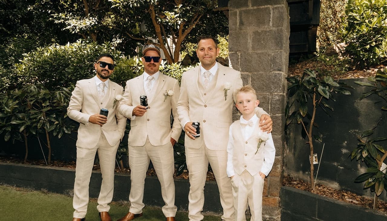 Nick, his groomsmen and a page boy in cream suits laughing in the garden