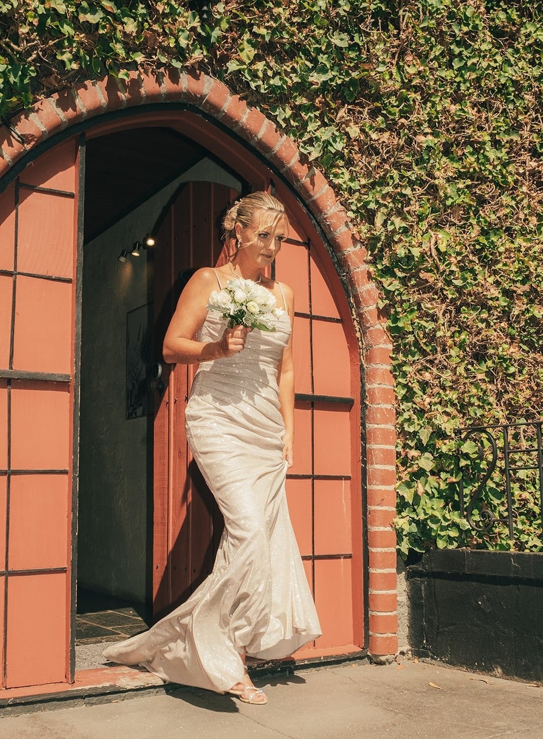 Jenna stepping out through the arched red door of the castle