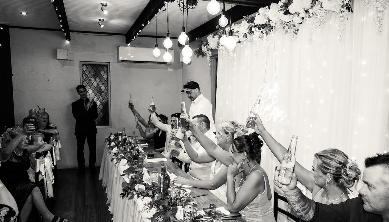 Black and white photo of the bridal table raising their glasses during the speeches