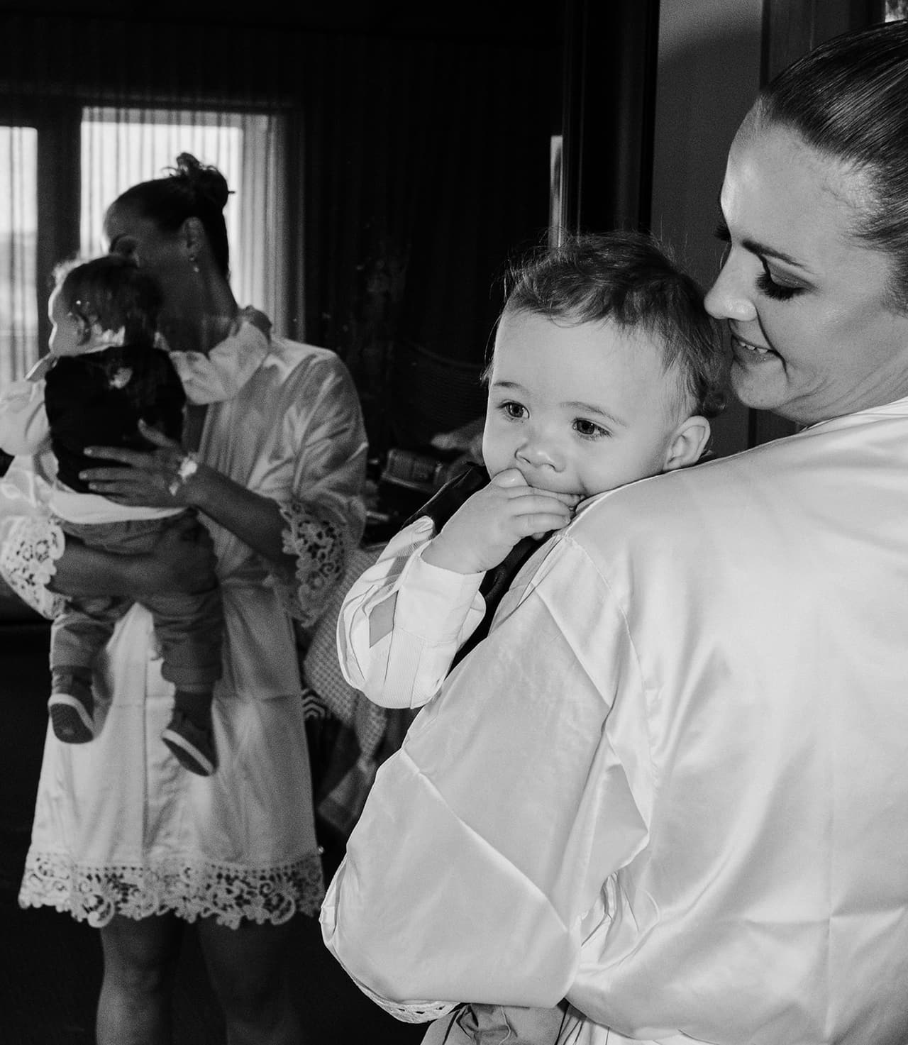 Black and white photo of Jessica in her robe cuddling a baby boy