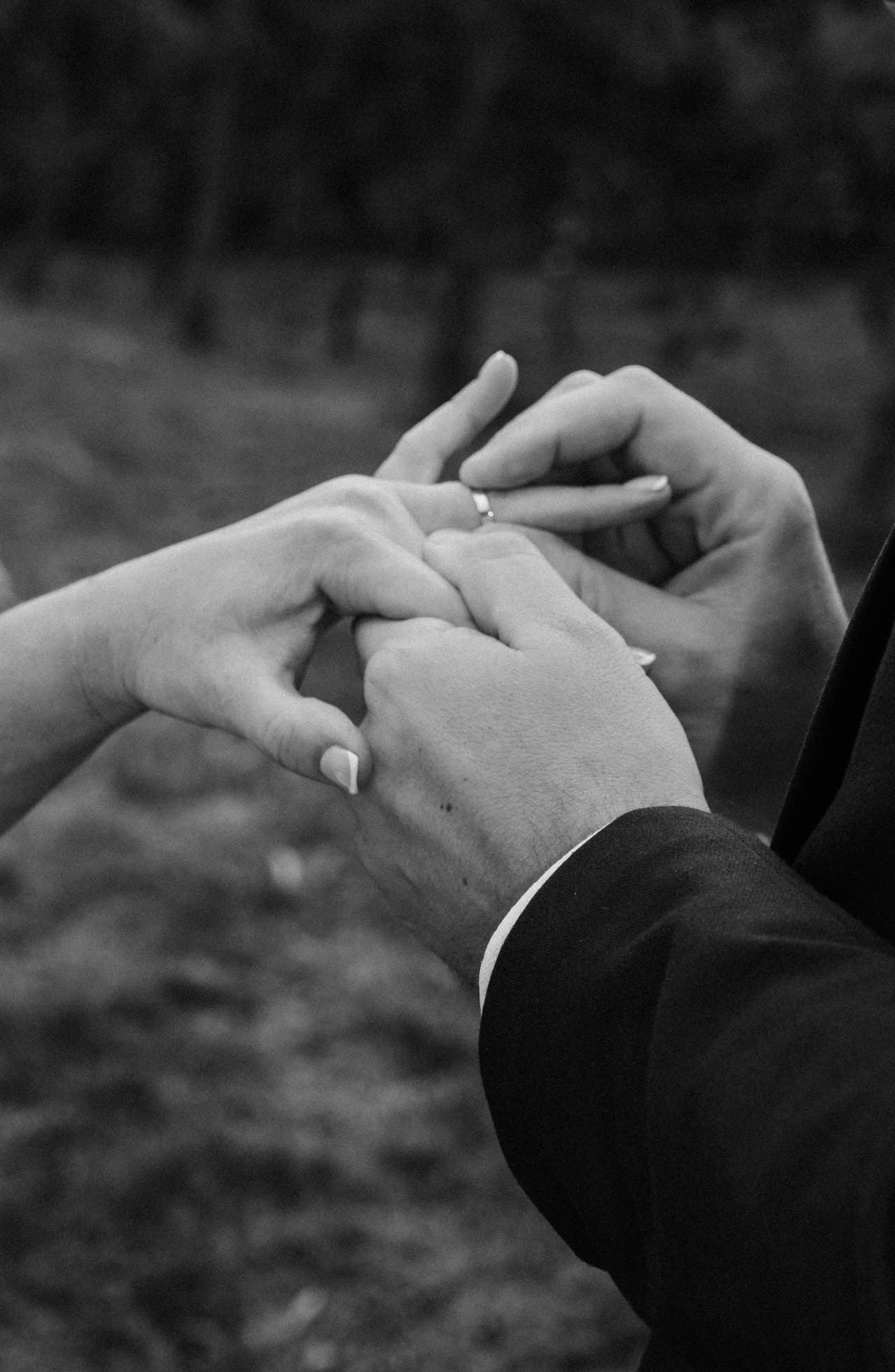 Black and white close up of Max slipping a ring onto Jessica’s finger