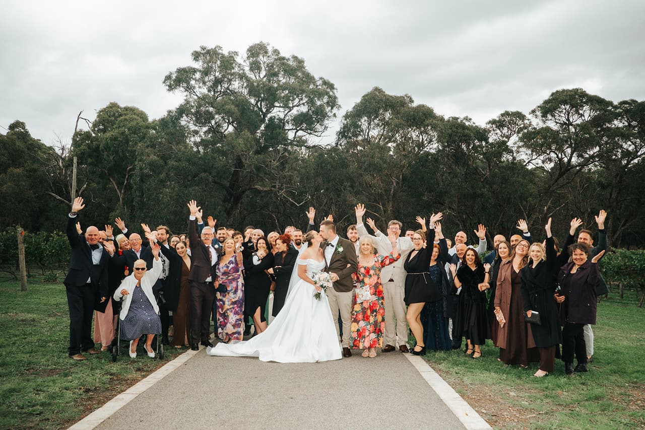 All the guests waving and cheering around Jessica and Max on the farm road