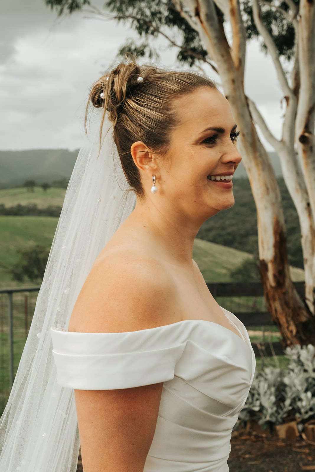 Jessica laughing in her veil beside a pale gum tree