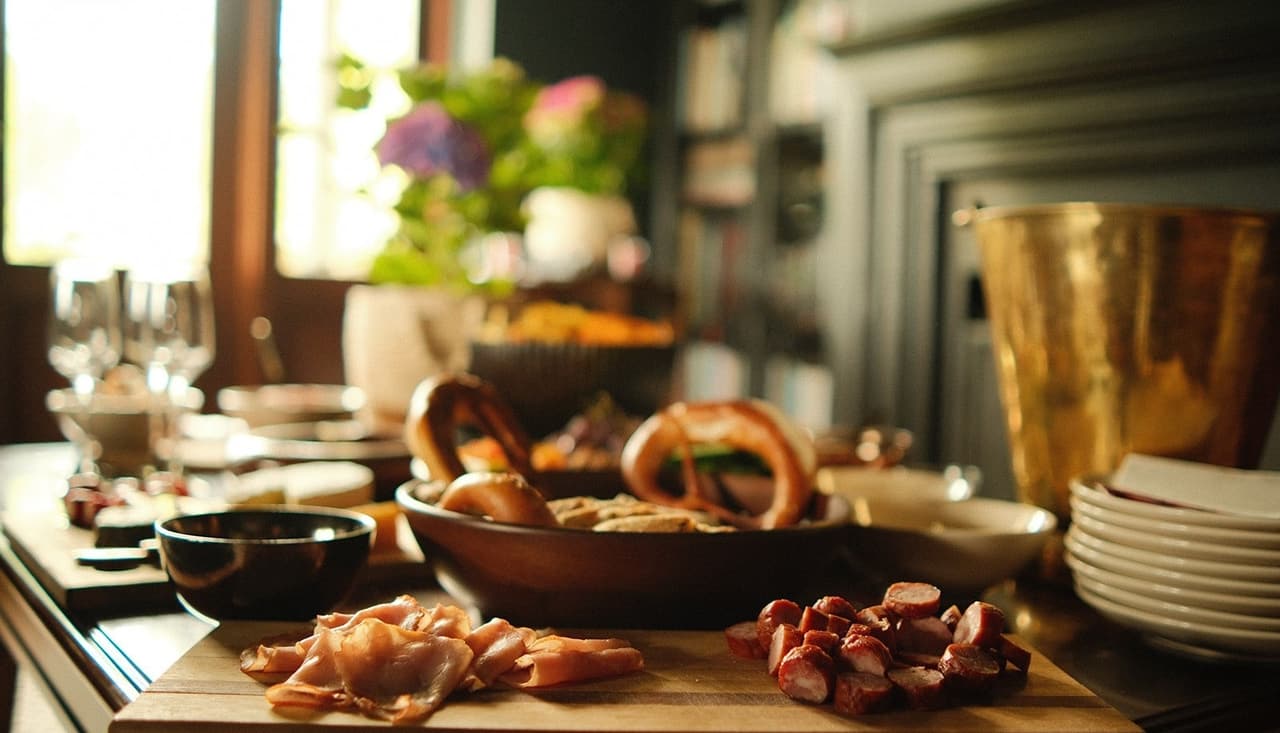 A grazing table of pretzels, bread and cured meats in warm window light