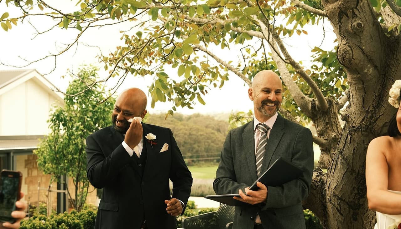 Krish wiping away a tear beside the celebrant during the ceremony