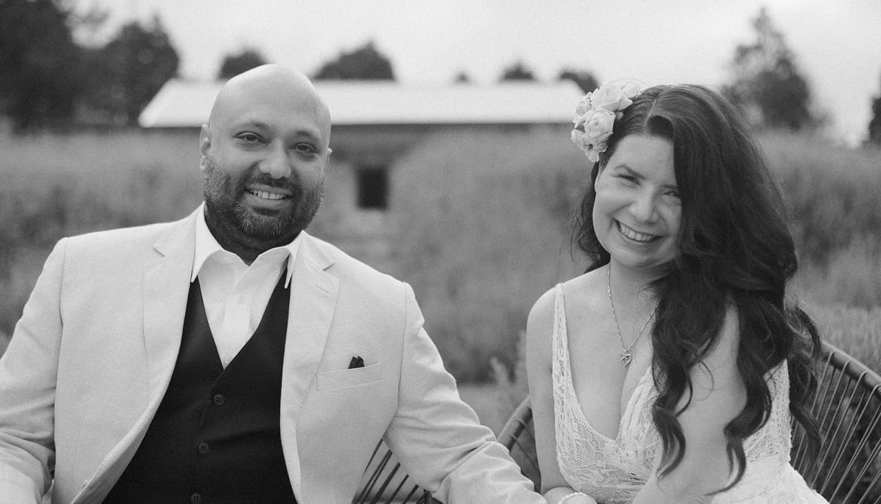 Black and white photo of Krish and Joanna laughing in their chairs on the terrace
