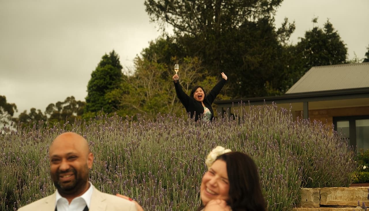 Krish and Joanna laughing in front of the lavender as someone cheers behind them