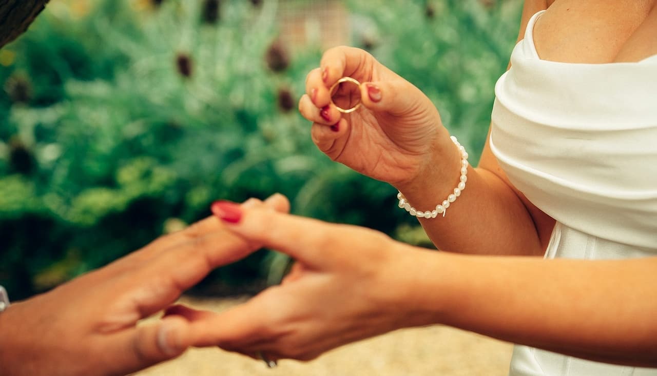 Close up of Joanna sliding a ring onto Krish’s finger