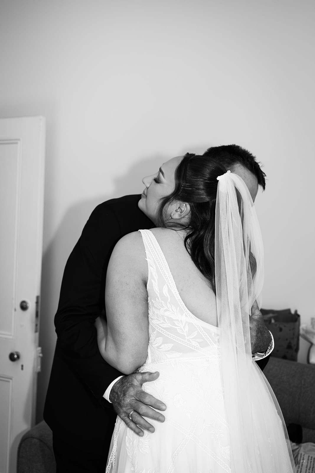 Black and white photo of Karina hugging her dad in her gown and veil
