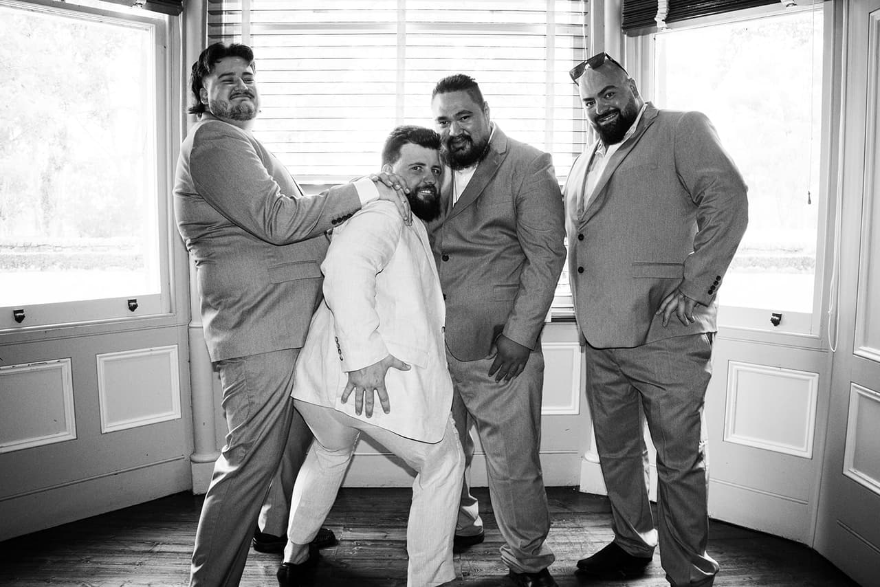 Black and white photo of Bronson and his groomsmen clowning around in the bay window