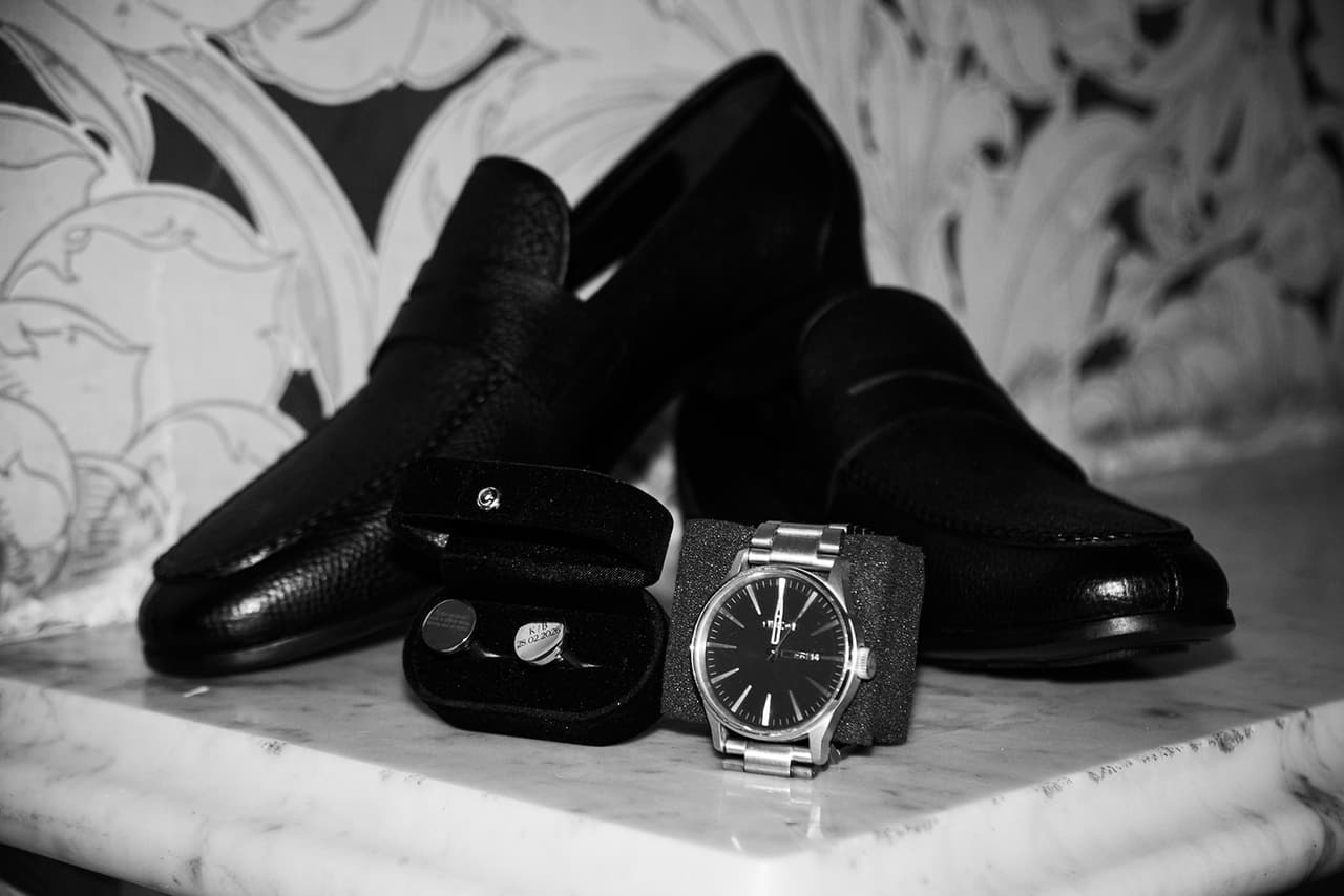 Black and white photo of Bronson’s black loafers, cufflinks and watch on a marble mantelpiece