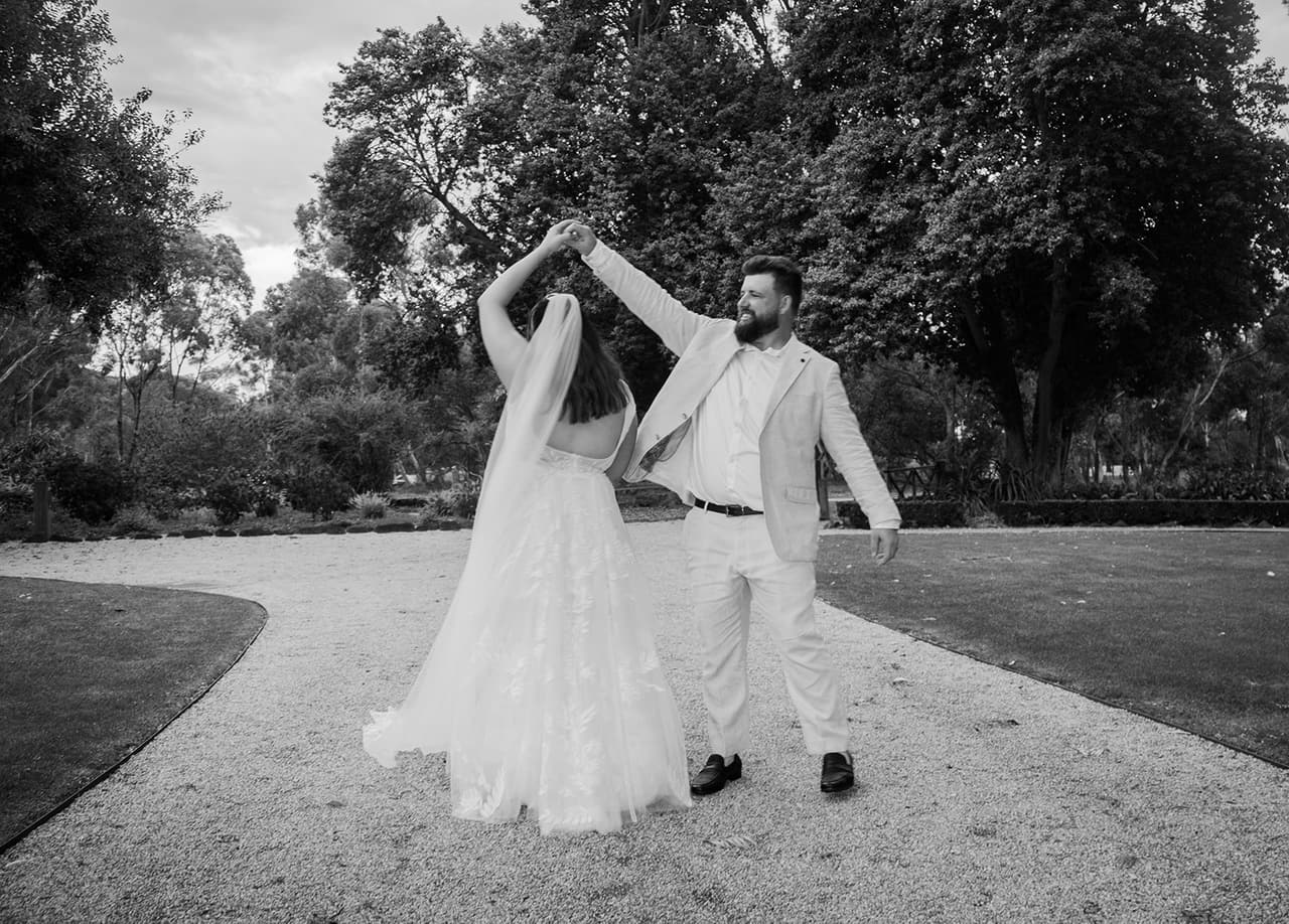 Black and white photo of Bronson twirling Karina on the gravel drive