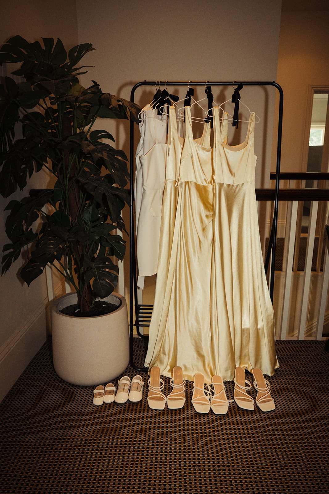 The bridesmaids' champagne dresses hanging on a rail, their shoes lined up underneath