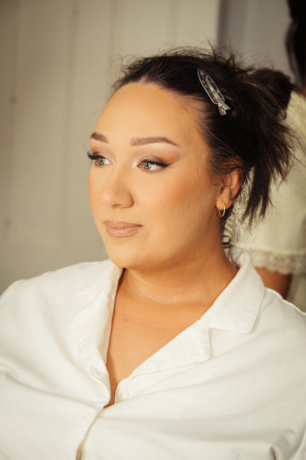 Karina in a white robe, her hair pinned up, looking off to one side