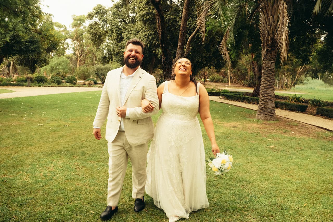 Karina and Bronson laughing as they walk arm in arm across the lawn