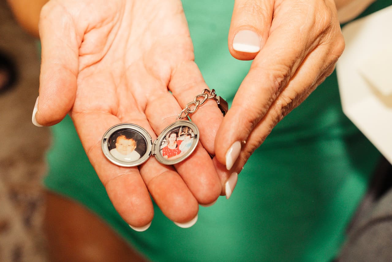 Two small photo lockets held open in a palm above a green dress