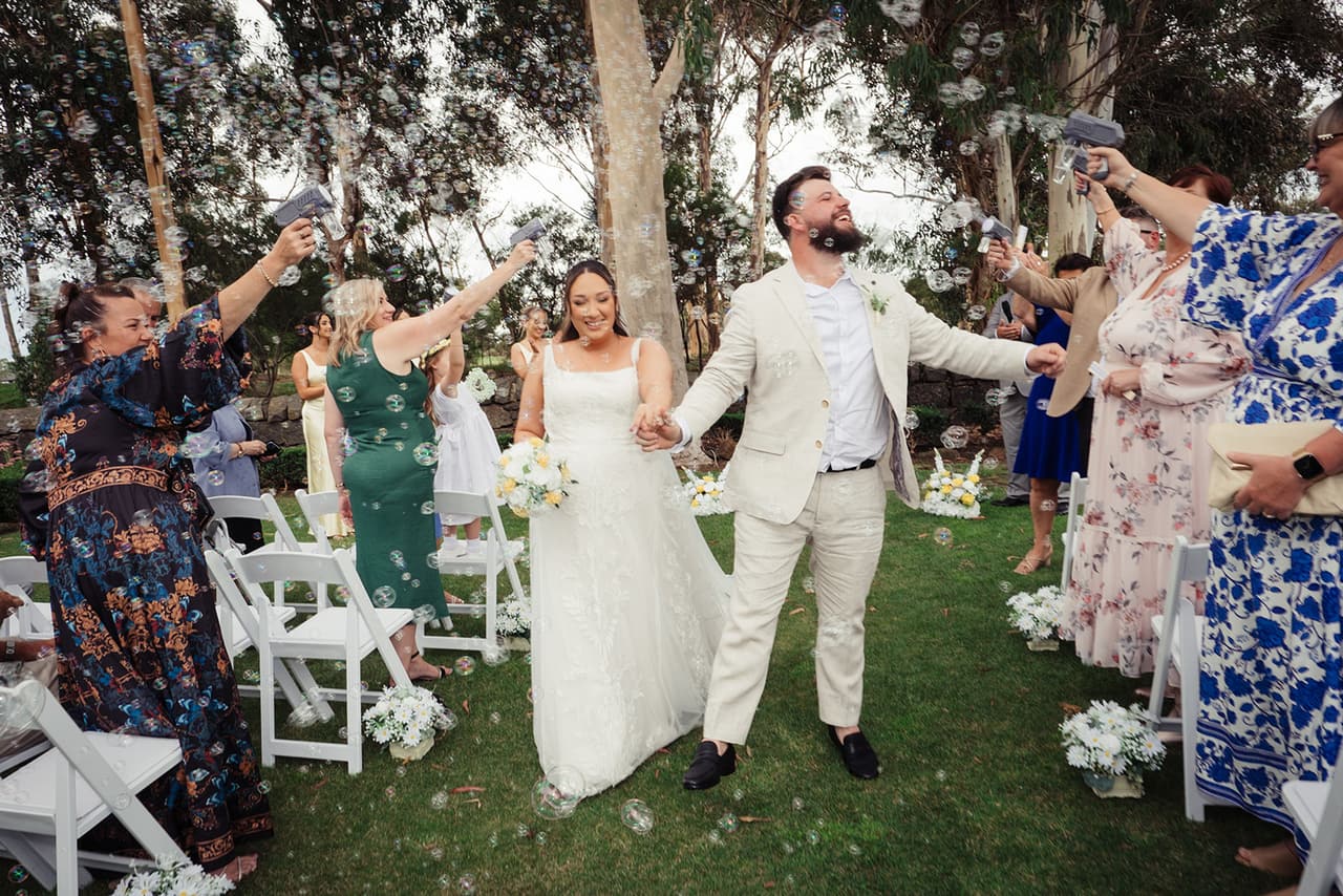 Guests cheering as Karina and Bronson walk back down the aisle together under the gums