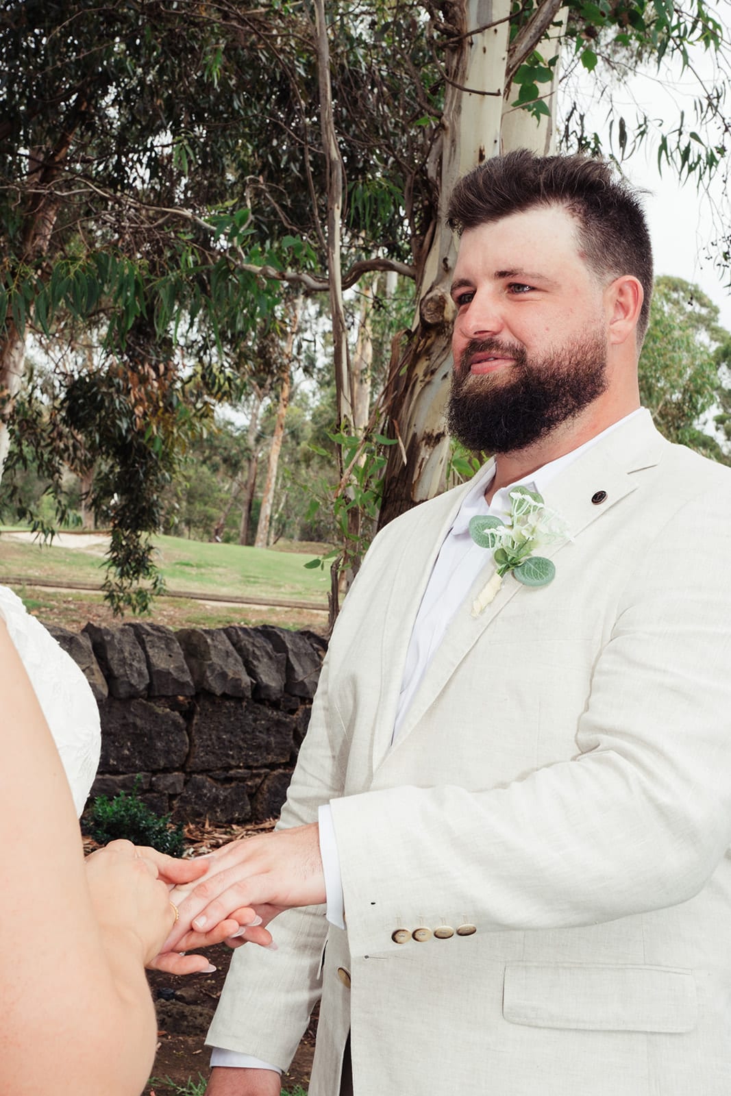 Bronson smiling as Karina slides the ring onto his finger