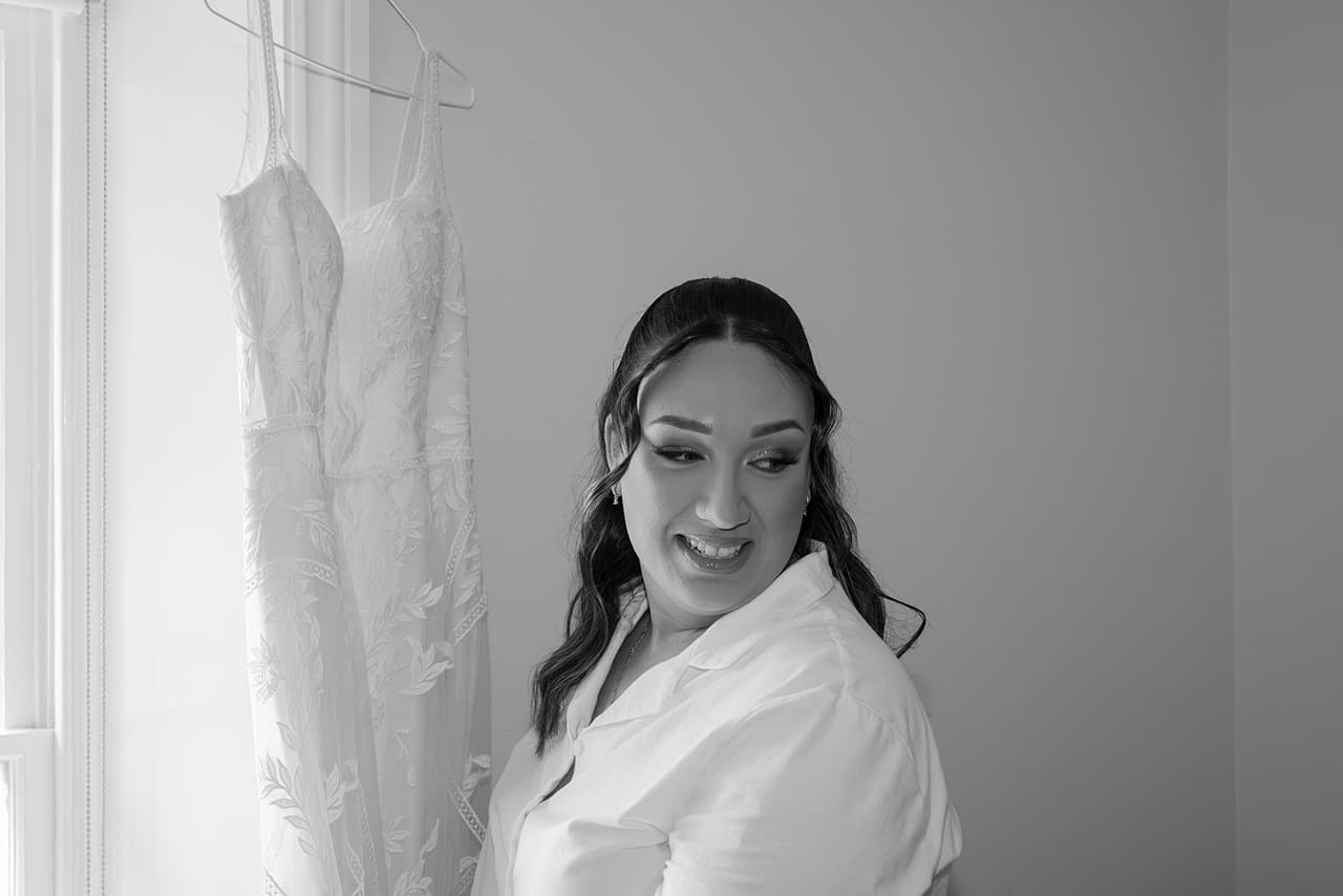 Black and white photo of Karina smiling over her shoulder, her dress hanging beside her