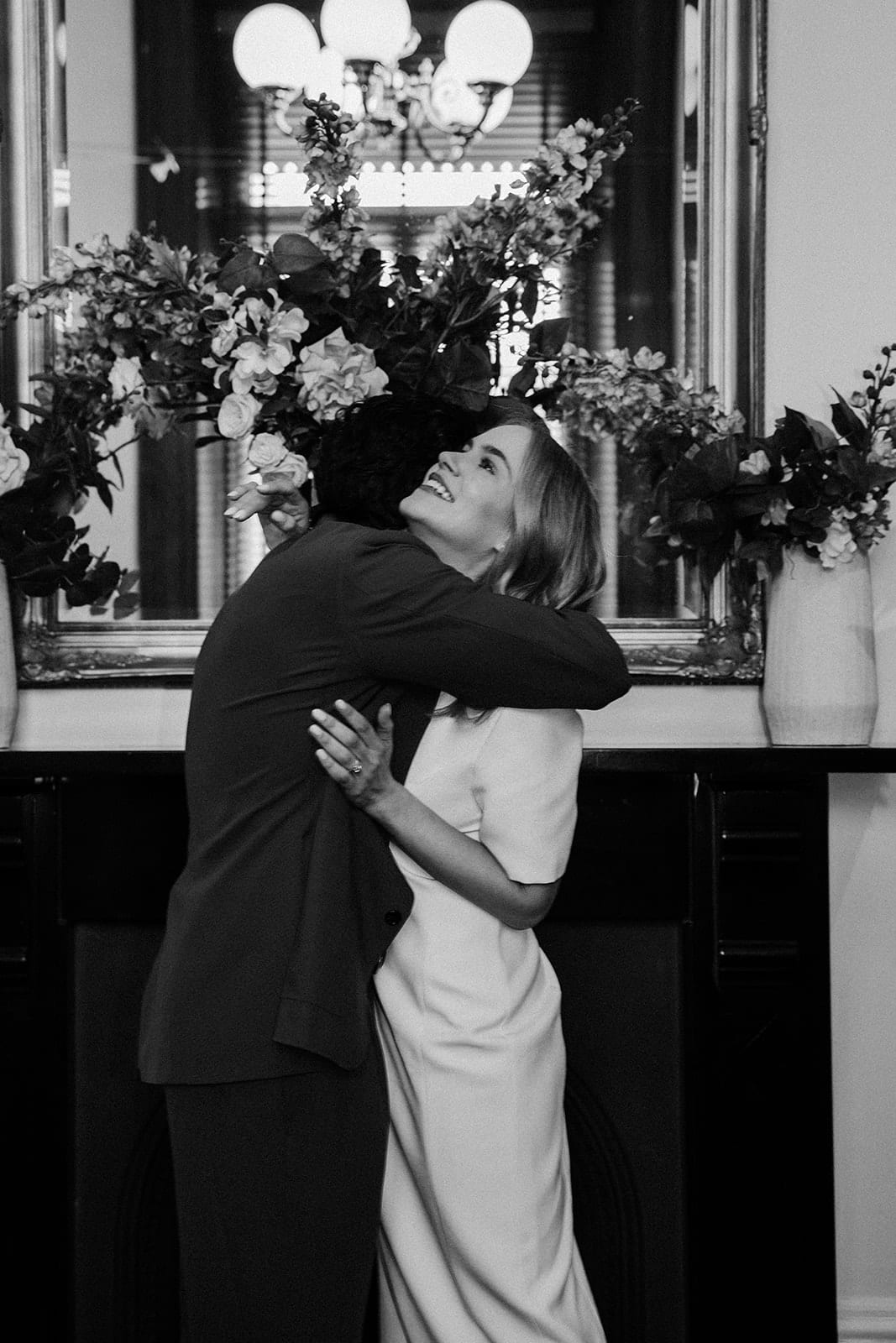 Black and white photo of Karina and Chris hugging by the fireplace