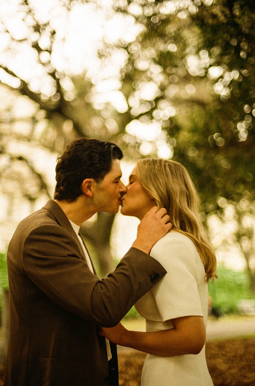 Karina and Chris kissing among the trees of Treasury Gardens, on 35mm film