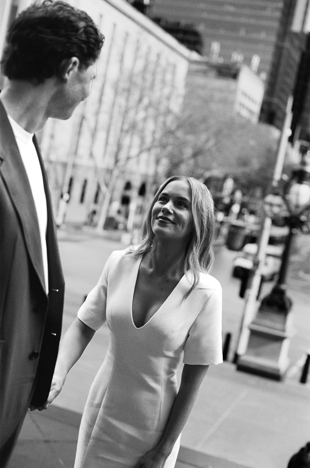 Black and white photo of Karina smiling up at Chris on a city footpath, on 35mm film