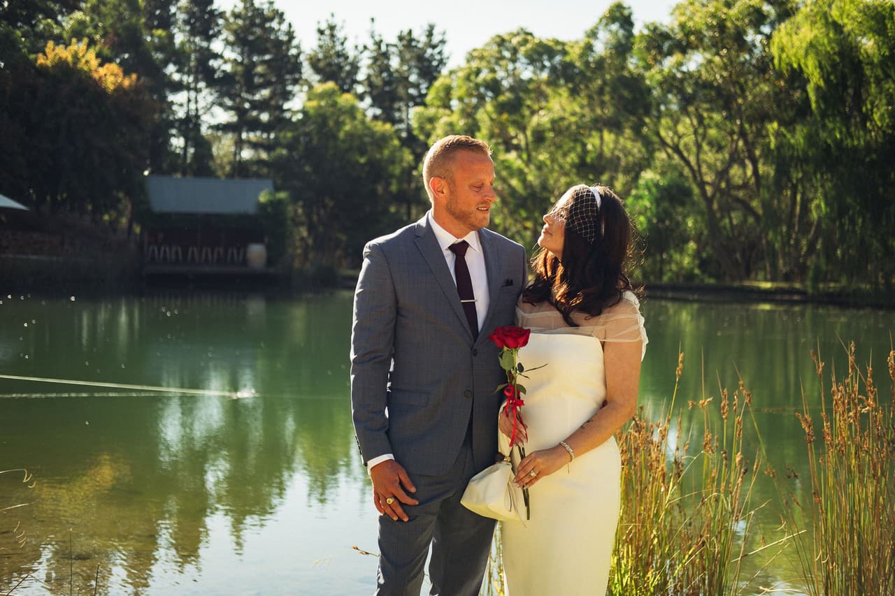 Ben and Kim smiling at each other on the bank of the pond in golden late afternoon light