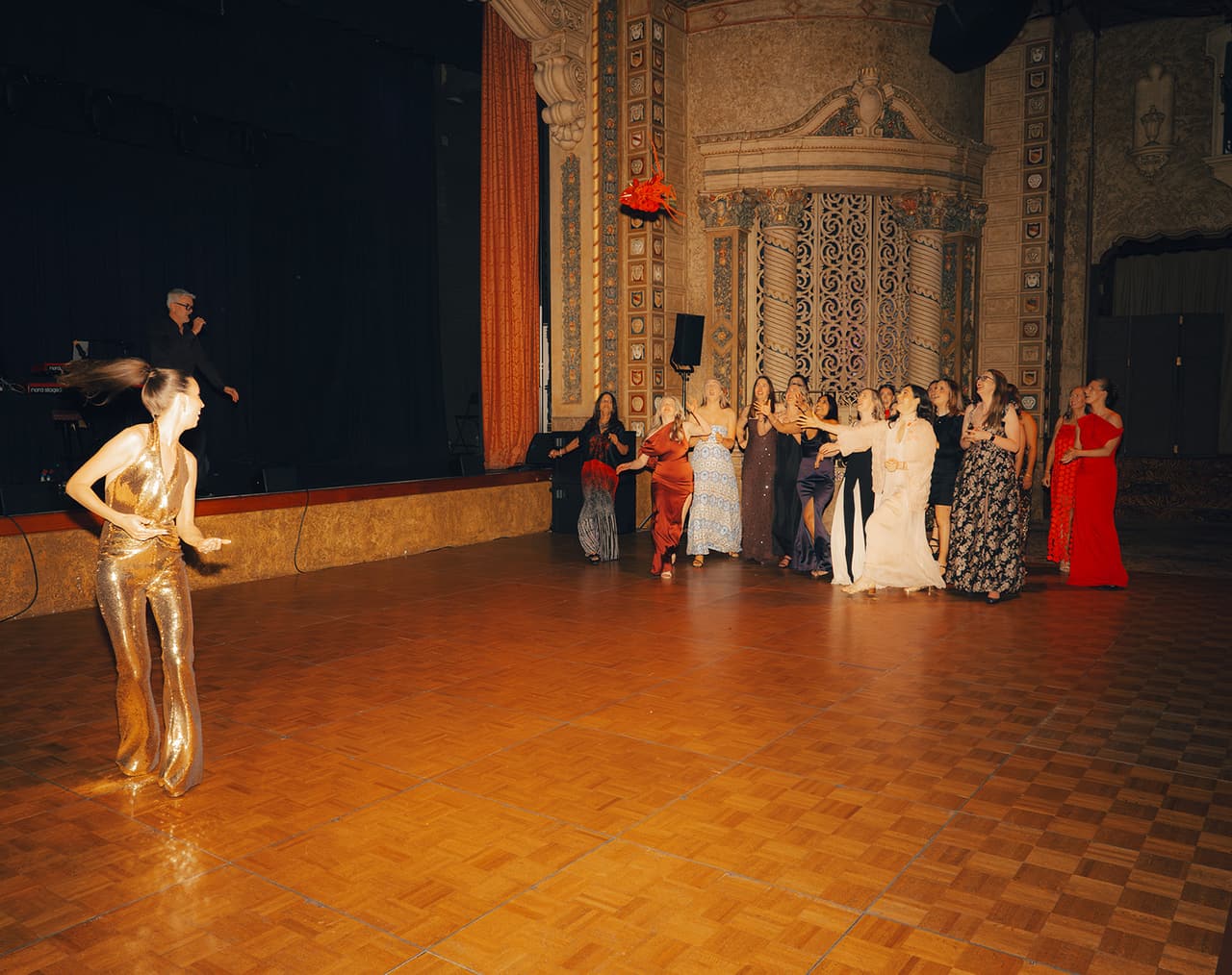 Kira tossing her bouquet over her head towards a group of guests on the dance floor