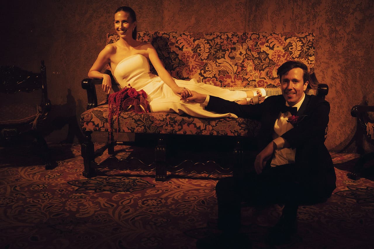 Kira reclining on a tapestry sofa in the Regent Theatre as Nick sits on the carpet beside her