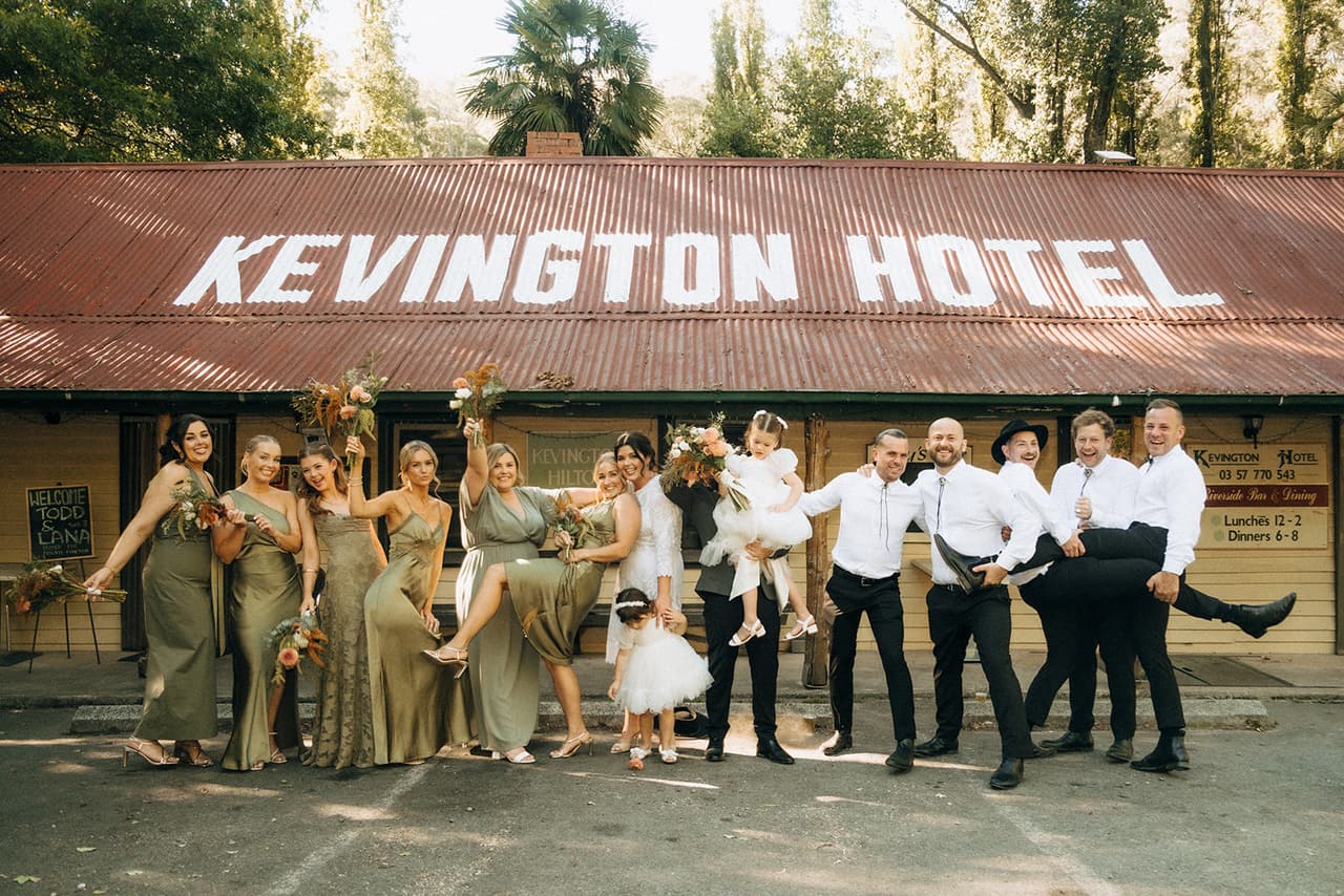The bridal party kicking up their legs in front of the Kevington Hotel