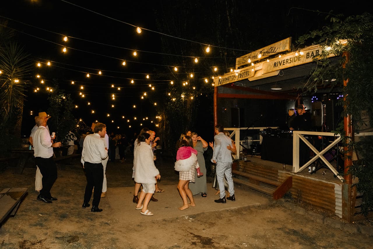 Guests dancing on the lawn under strings of festoon lights