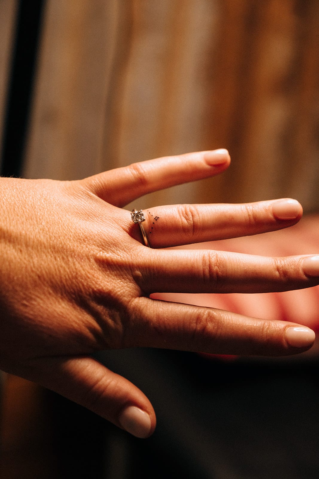 Lana’s hand with a fine new tattoo of dots and a tiny star beside her engagement ring