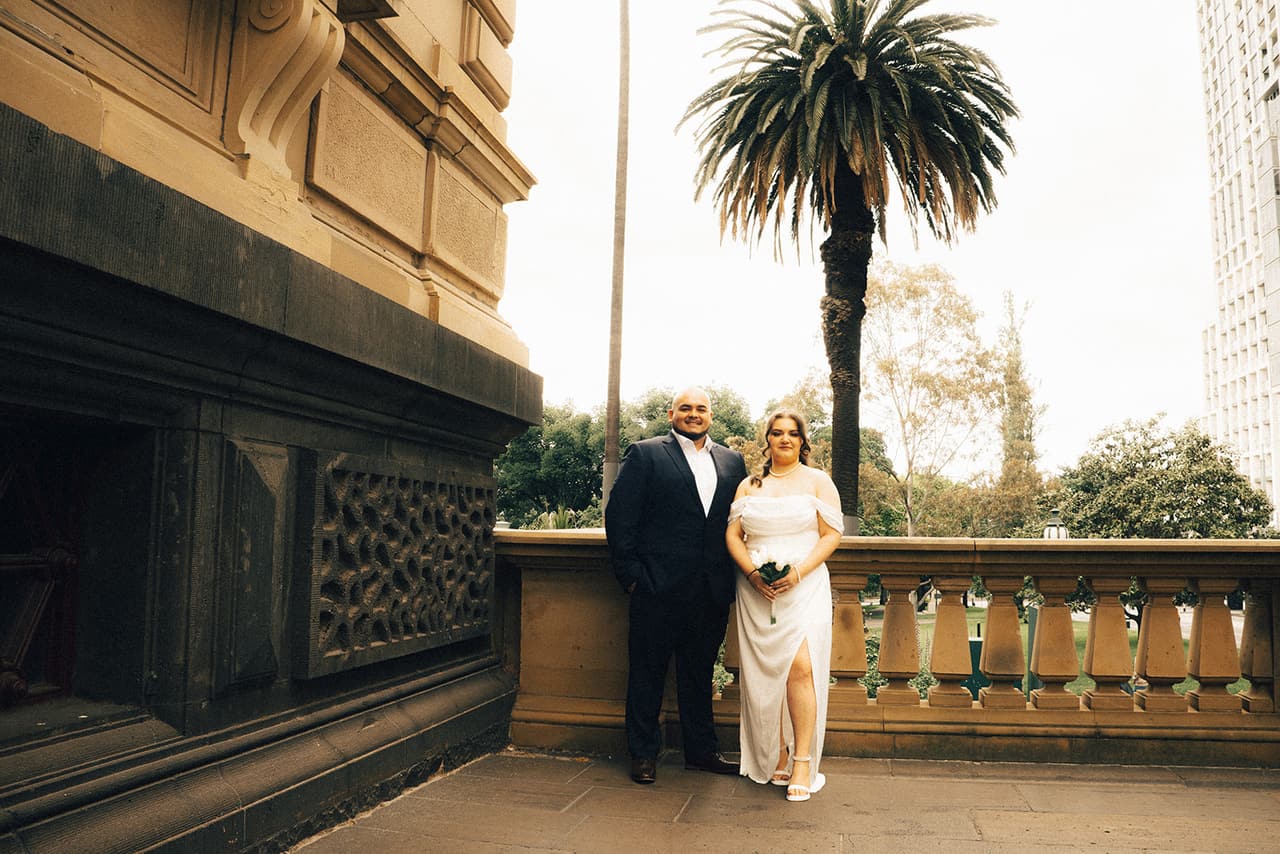 Martina and Diego on the sandstone balcony of the Old Treasury Building, a palm tree behind them