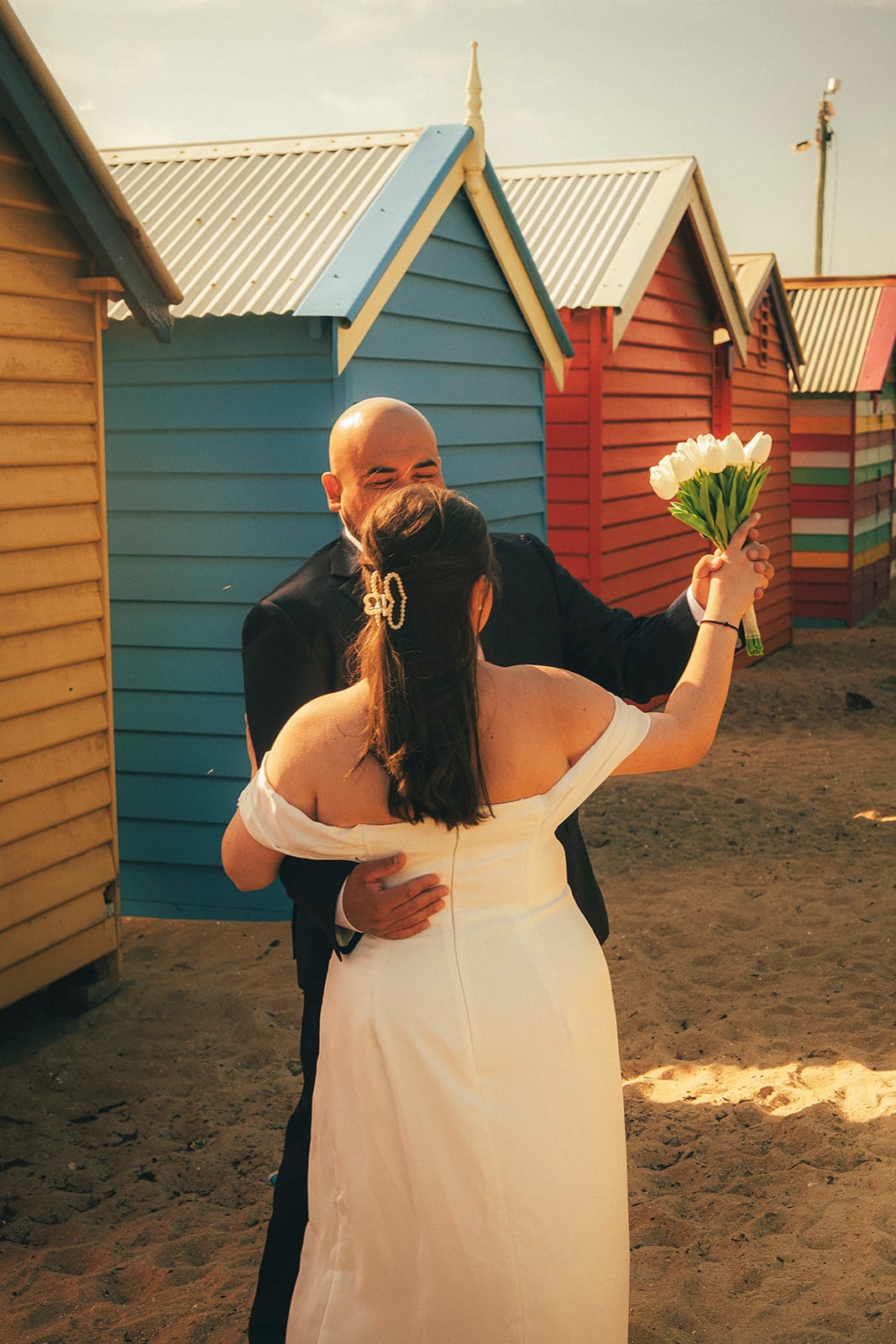 Martina raising her bouquet beside the colourful bathing boxes