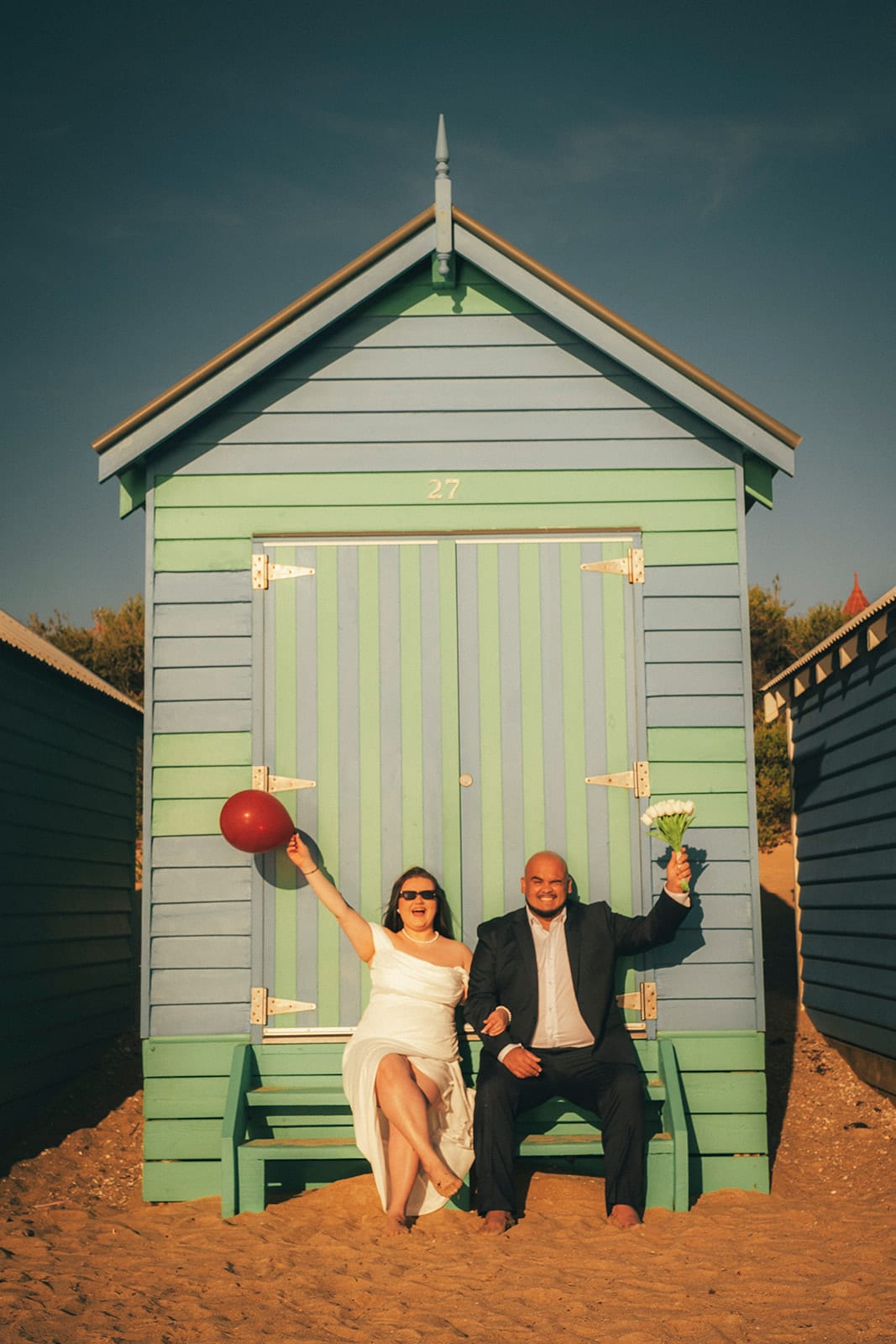 Martina and Diego cheering in the open doorway of a bathing box