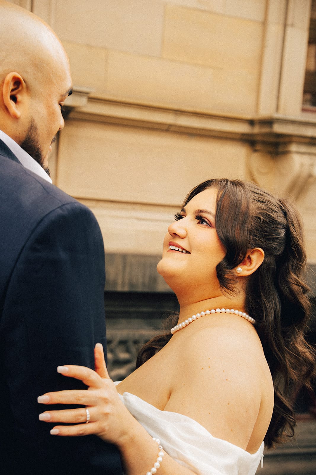 Martina smiling up at Diego with her hand on his arm beside the sandstone wall