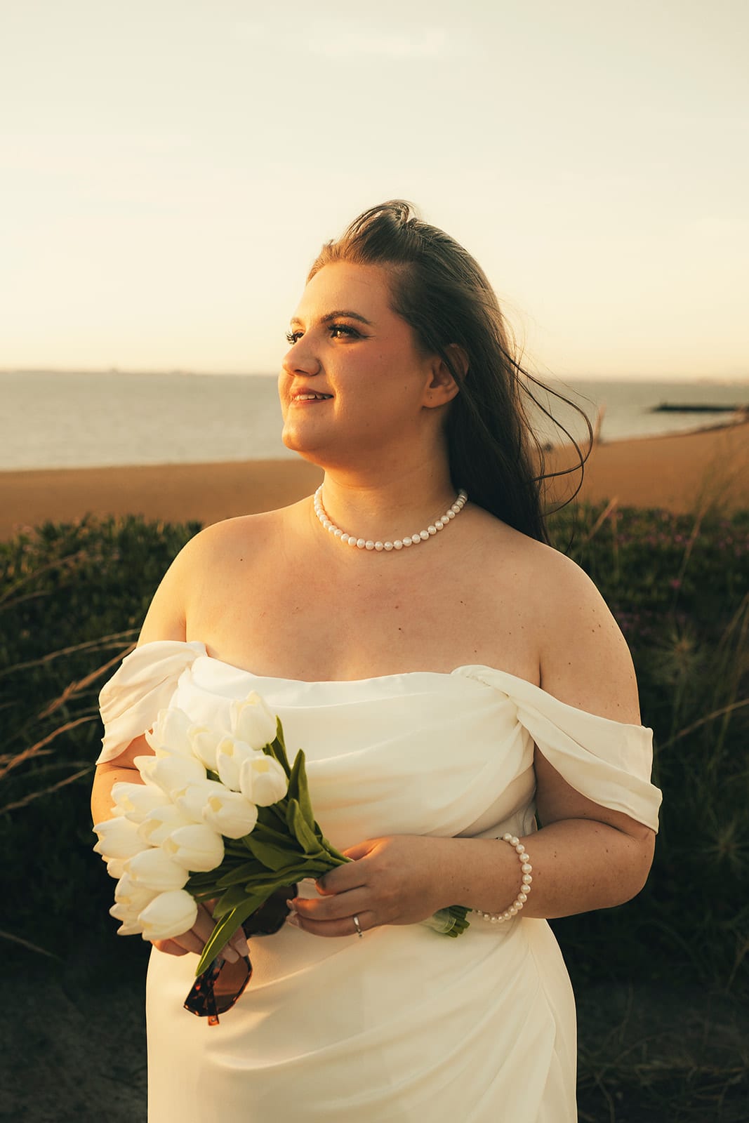 Martina holding her white tulips in the golden evening light above the beach