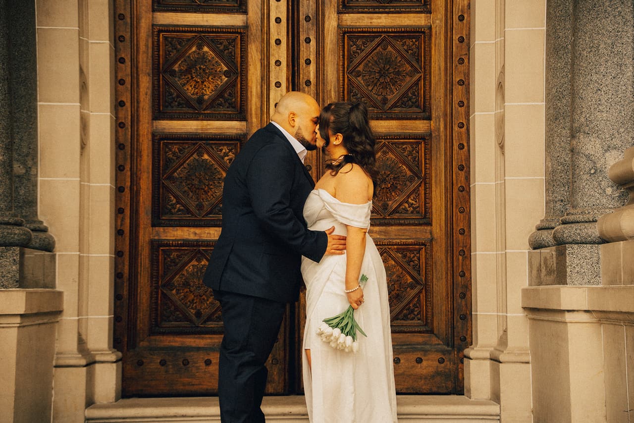Martina and Diego kissing at the huge carved doors of Parliament House
