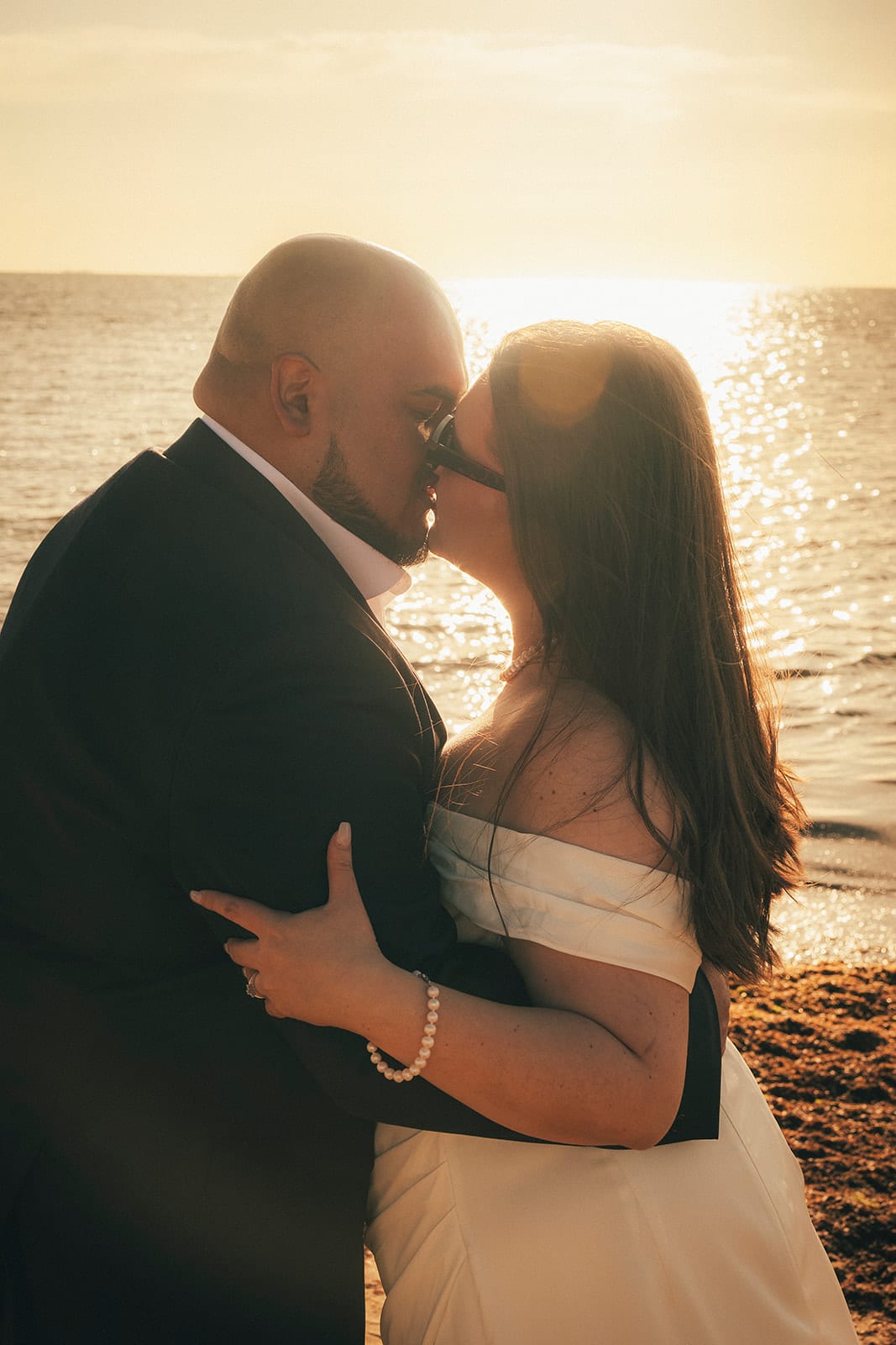 Martina and Diego kissing in the low sun at the water’s edge