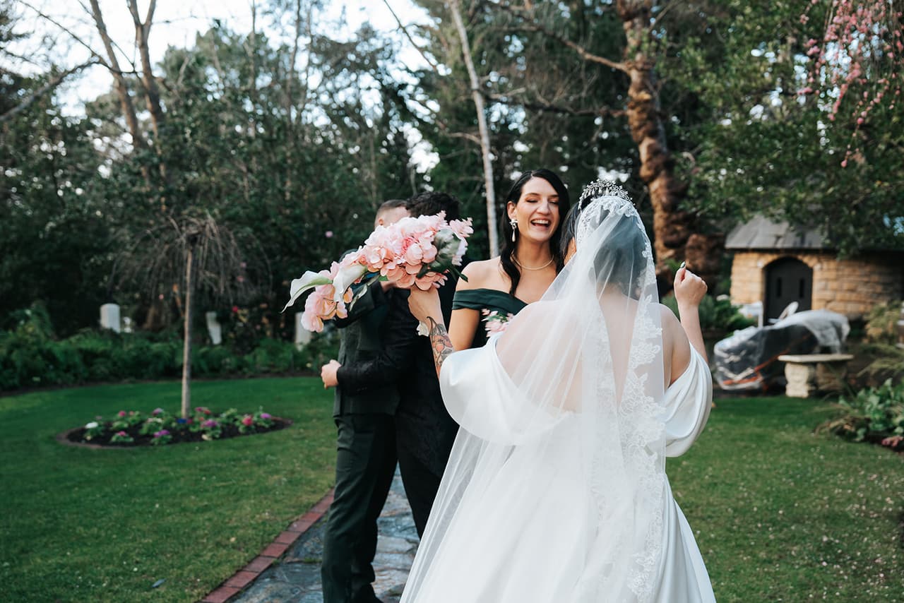 Porscha raising her bouquet high on the lawn after the ceremony