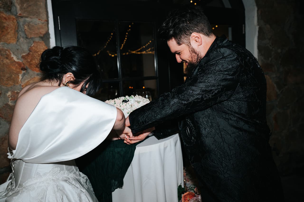 Porscha and Jordan cutting the cake beneath a stone archway