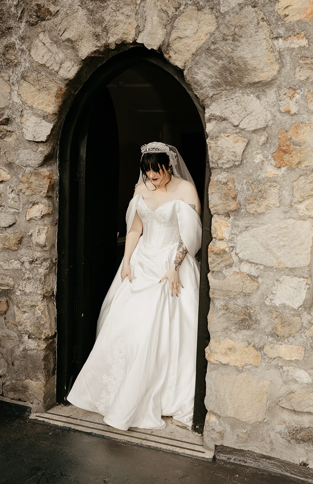Porscha stepping out of a narrow stone archway on the castle terrace for the first look