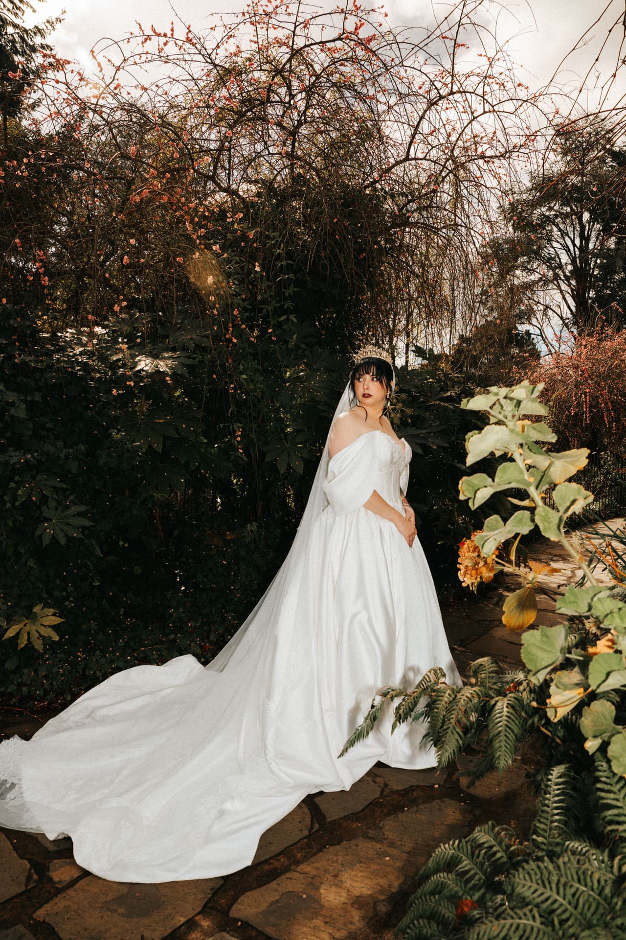 Porscha in a long-train gown standing in a leafy autumn garden