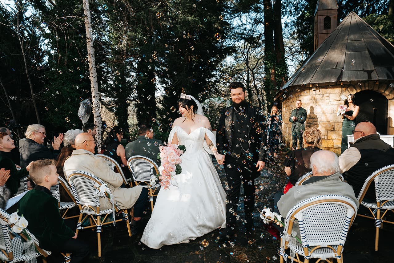 Porscha and Jordan walking out through their guests in a shower of petals