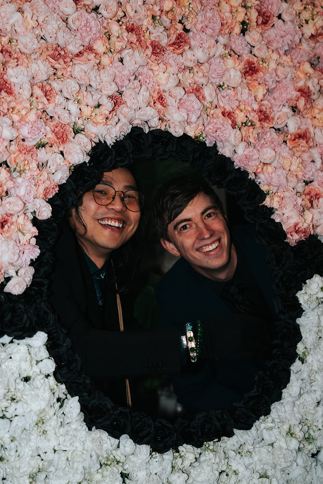 Two guests grinning through the centre of the flower Poké Ball