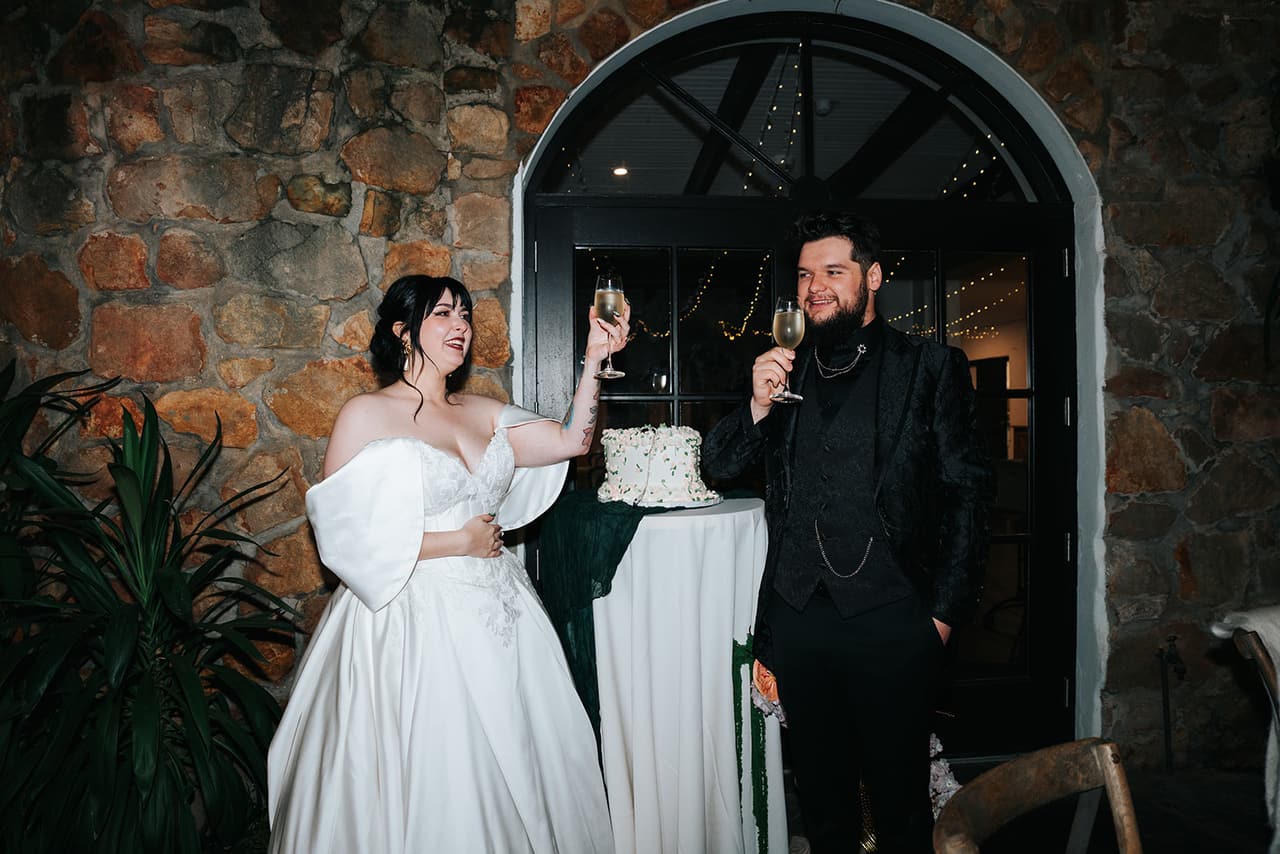 Porscha and Jordan raising their glasses beside the cake